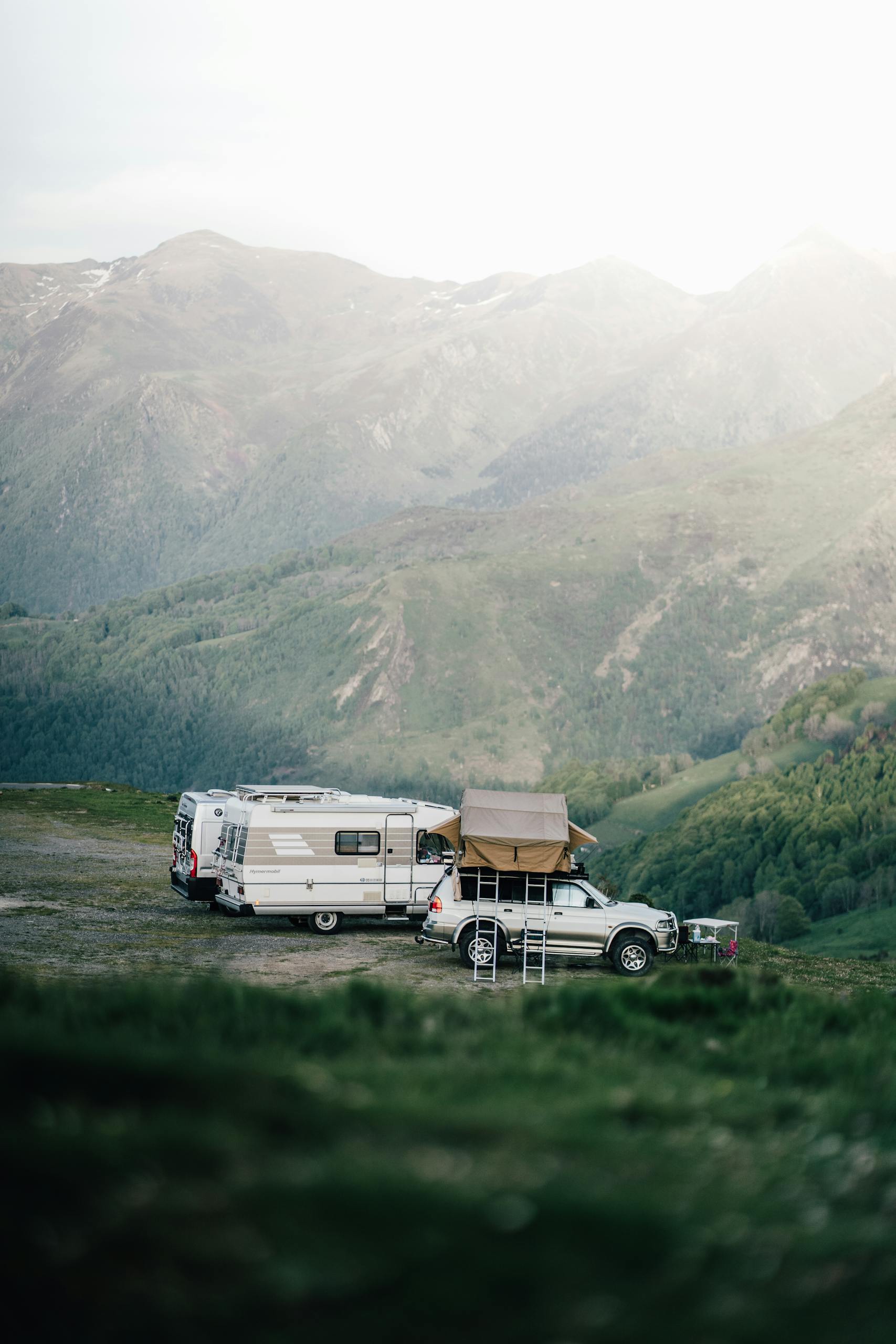A car and camper van set up camp in a serene mountainous landscape, perfect for an adventurous escape in Russia